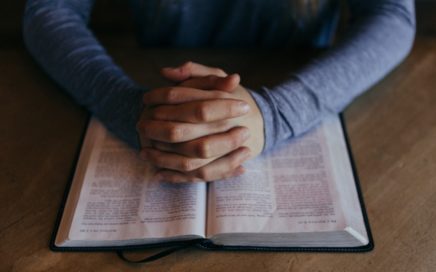 man holding his hands on open book